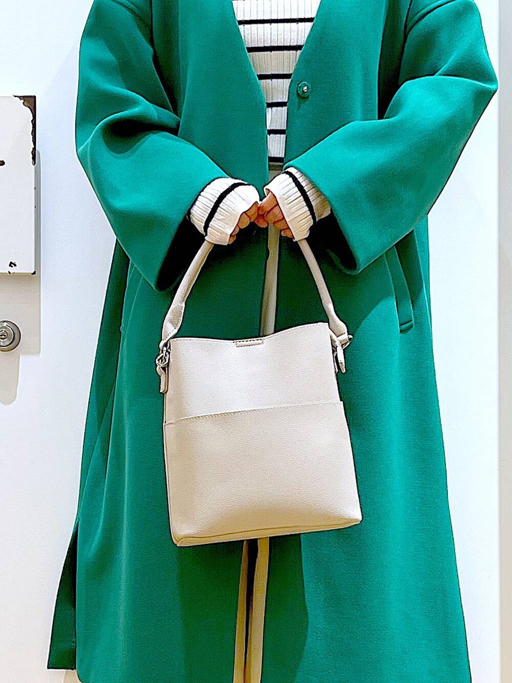 グレー系のショルダーバッグ、ホワイト系のニット/セーター、ベージュ系のブーツを着用したレディースの冬コーディネートの9枚目の写真