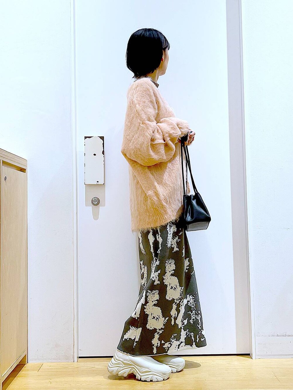 グレー系のスカート、ブラック系のトートバッグ、ピンク系のカーディガン/ボレロを着用したレディースの秋コーディネートの4枚目の写真