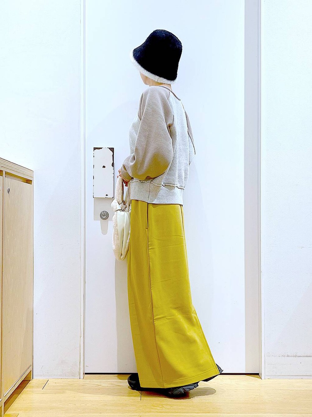 ホワイト系のショルダーバッグ、ブラック系のブーツ、ベージュ系のニット/セーターを着用したレディースの冬コーディネートの3枚目の写真