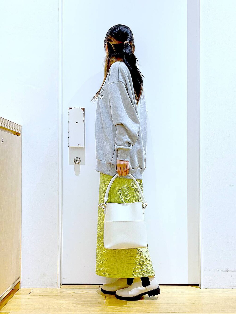 グリーン系のスカート、グレー系のスウェット、ホワイト系のショルダーバッグを着用したレディースの春コーディネートの3枚目の写真