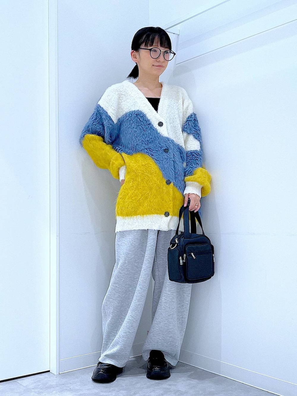ブラック系のショルダーバッグ、ブラック系のローファー、イエロー系のカーディガン/ボレロを着用したレディースの秋コーディネートの2枚目の写真
