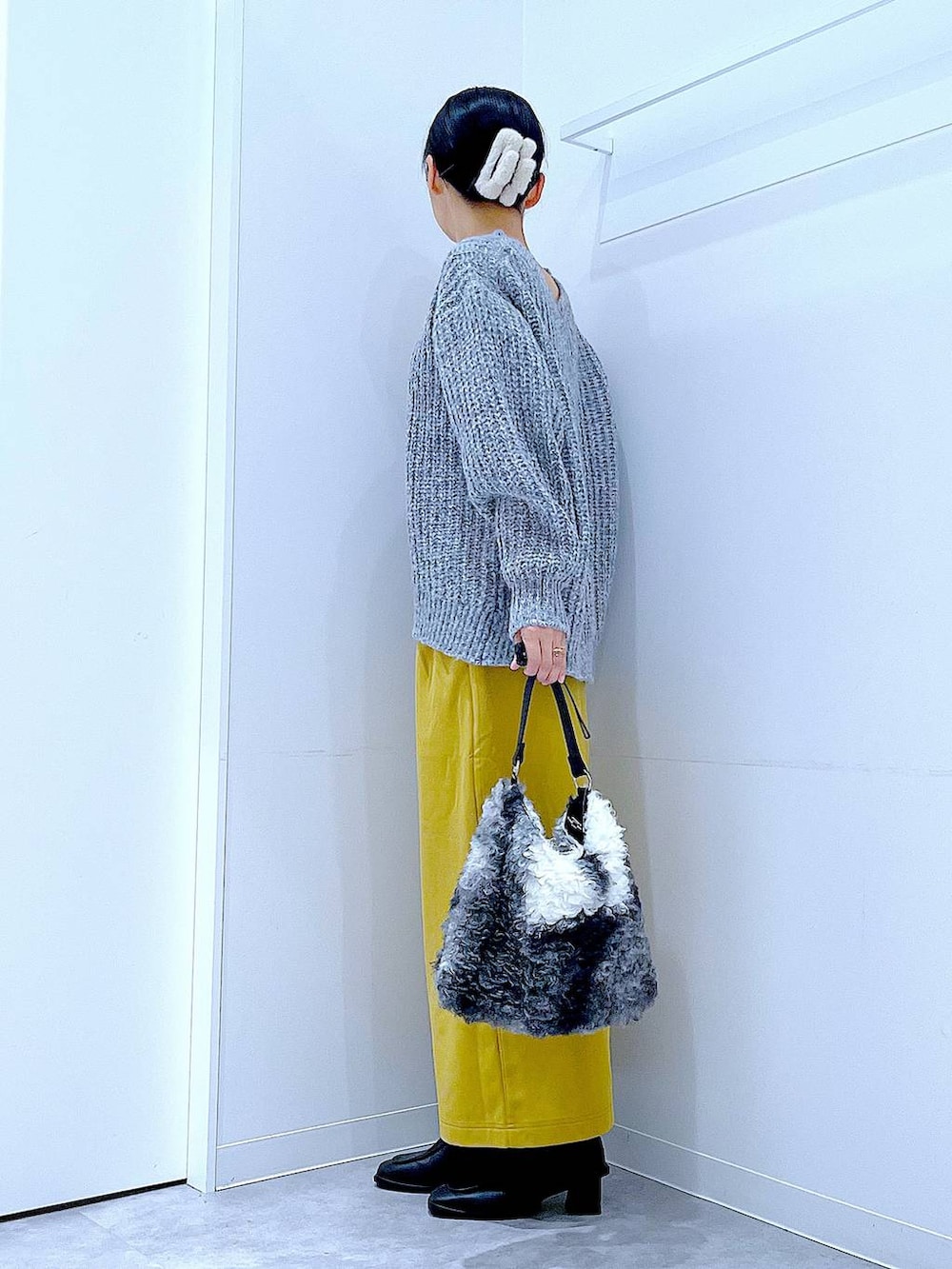 グレー系のニット/セーター、イエロー系のスカート、ブラック系のブーツを着用したレディースの冬コーディネートの3枚目の写真