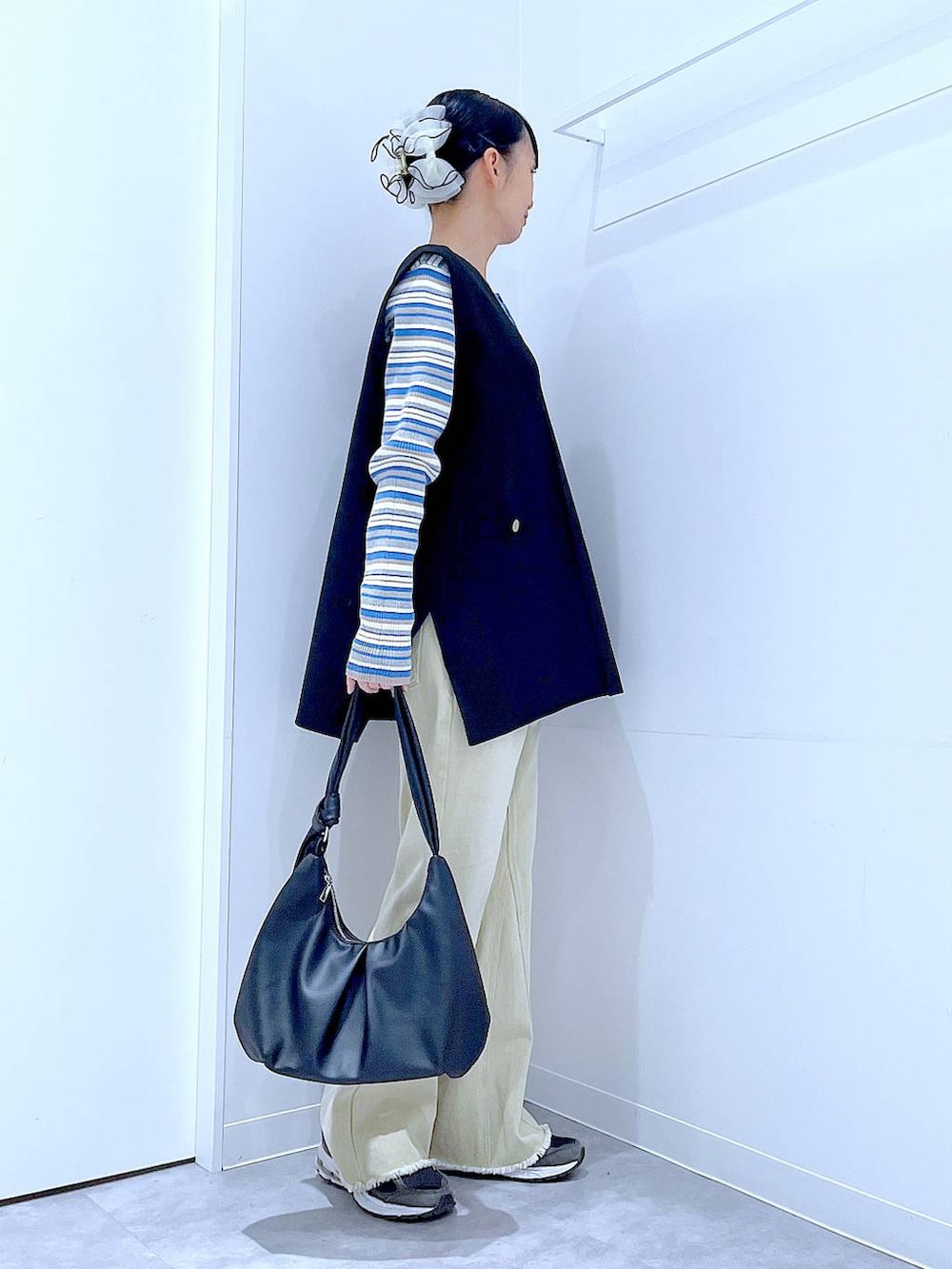 ブルー系のニット/セーター、ブラック系のベスト、ベージュ系のデニムパンツを着用したレディースの冬コーディネートの4枚目の写真