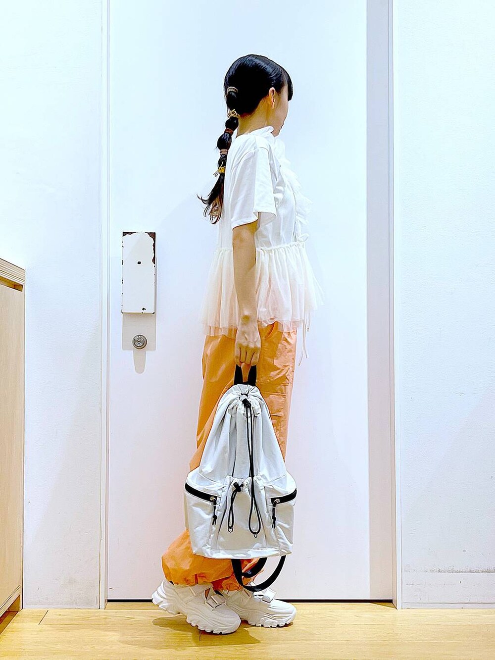 ホワイト系のスニーカー、ホワイト系のショルダーバッグ、オレンジ系のカーゴパンツを着用したレディースの夏コーディネートの4枚目の写真