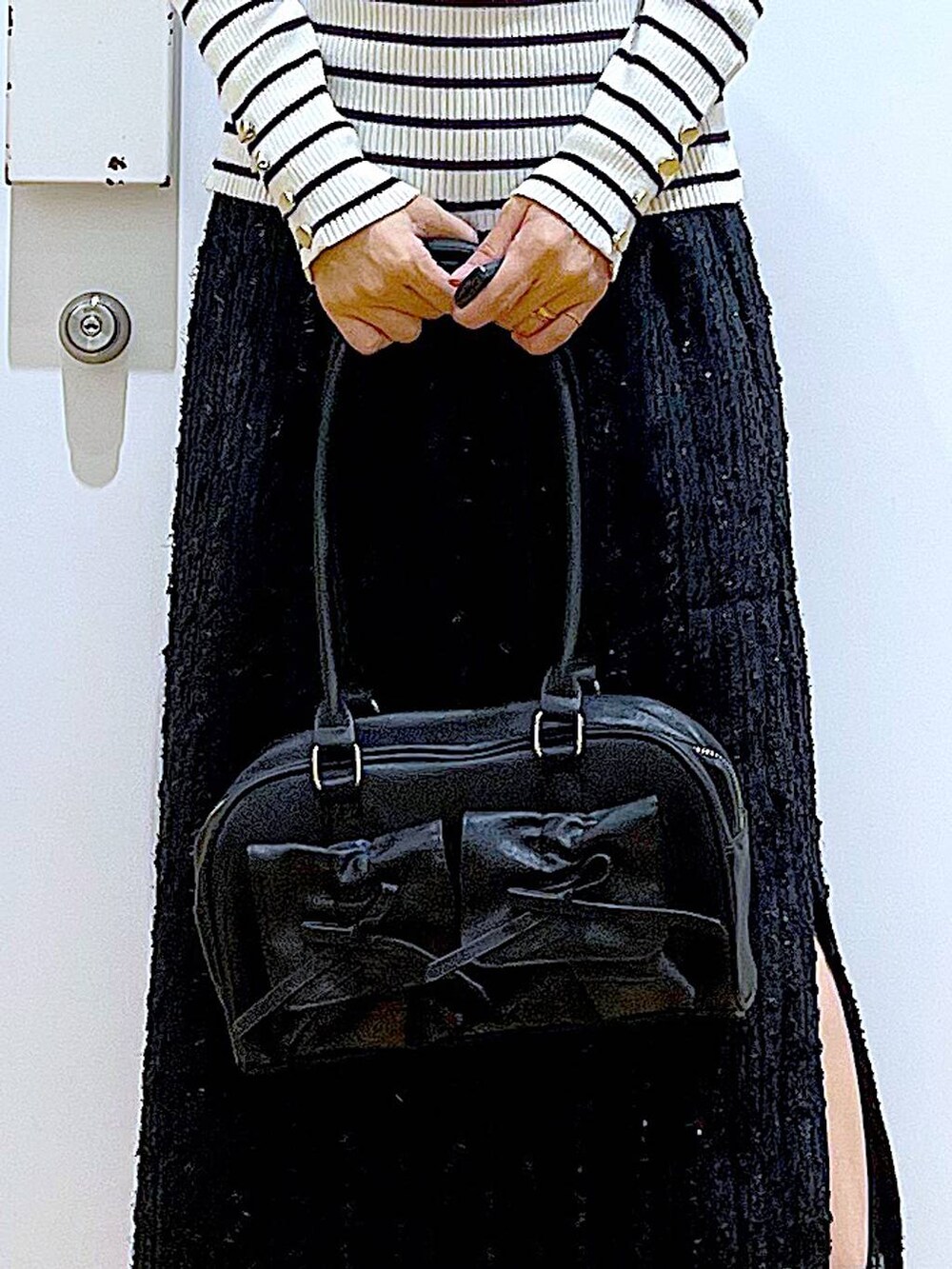 ホワイト系のニット/セーター、ブラック系のハンドバッグ、ブラック系のブーツを着用したレディースの秋コーディネートの9枚目の写真