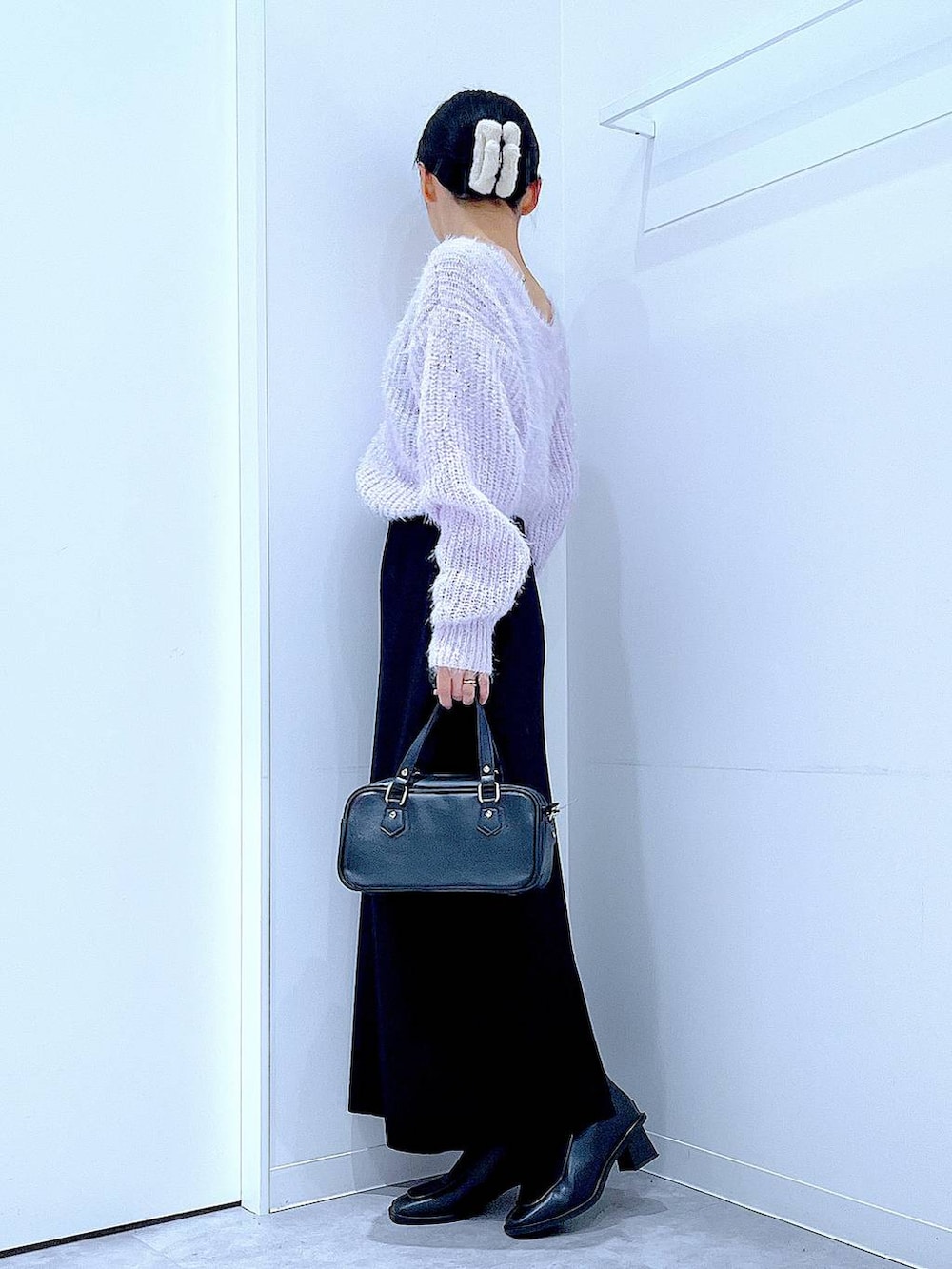 ブラック系のブーツ、ブラック系のショルダーバッグ、ブラック系のスカートを着用したレディースの冬コーディネートの3枚目の写真