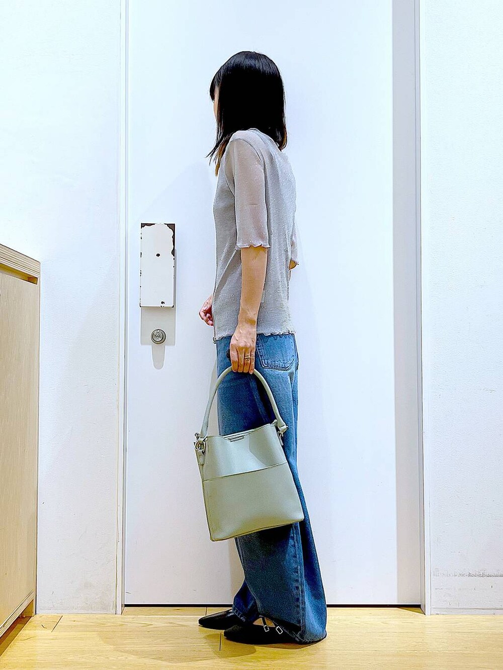 グレー系のTシャツ/カットソー、ブルー系のデニムパンツ、グリーン系のショルダーバッグを着用したレディースの秋コーディネートの3枚目の写真