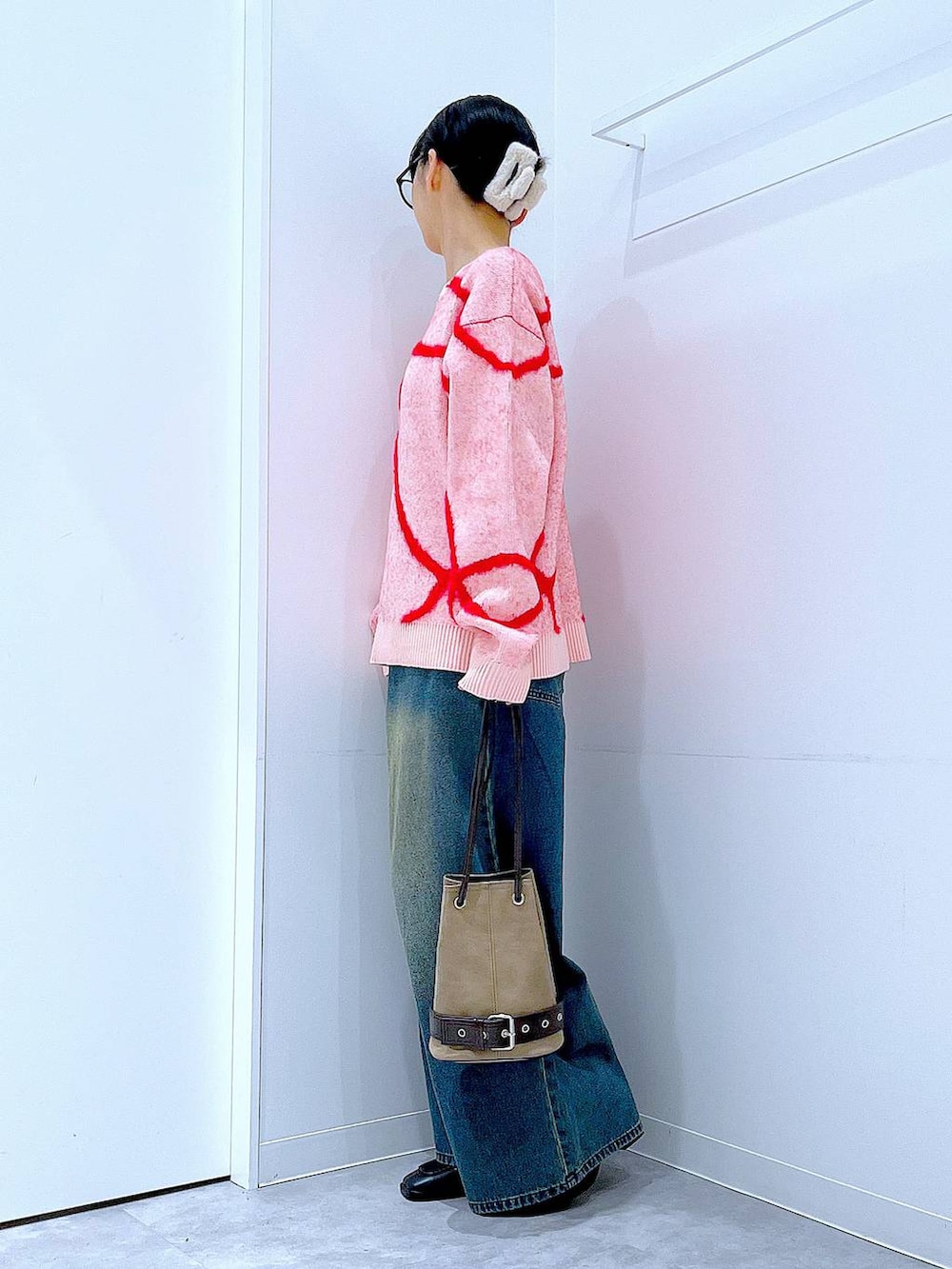 ブルー系のデニムパンツ、ブラック系のブーツ、ベージュ系のハンドバッグを着用したレディースの冬コーディネートの3枚目の写真