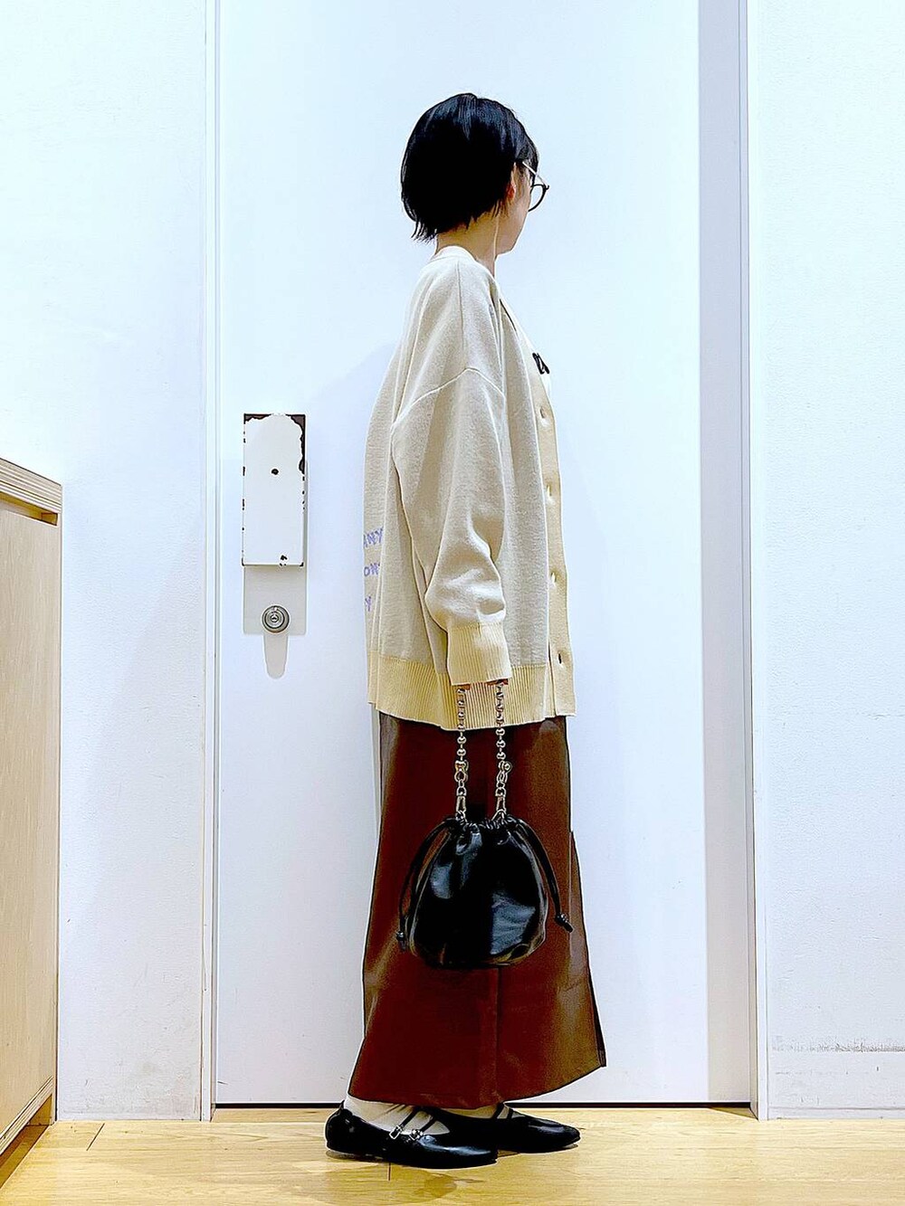 ブラウン系のスカート、ブラック系のショルダーバッグ、ブラック系のパンプスを着用したレディースの秋コーディネートの4枚目の写真