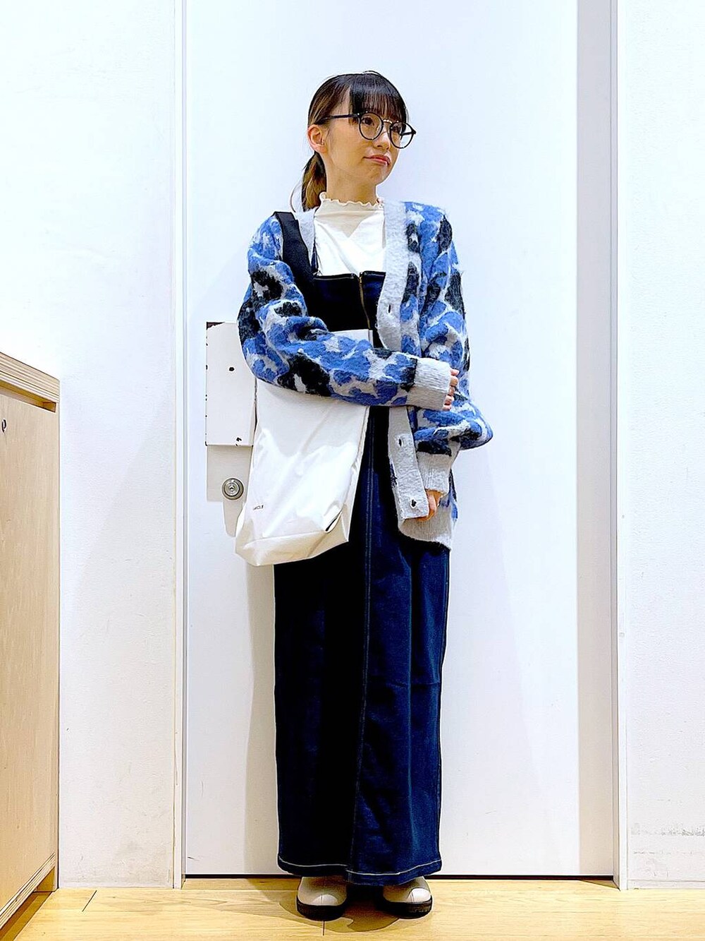 ブルー系のジャンパースカート、ホワイト系のTシャツ/カットソー、ベージュ系のブーツを着用したレディースの冬コーディネートの2枚目の写真