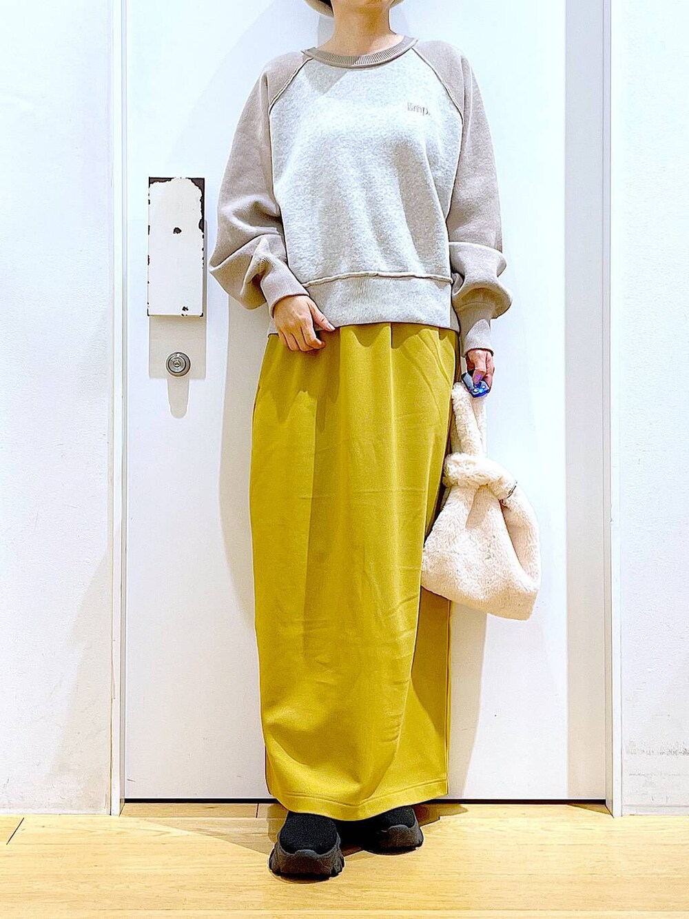 ホワイト系のショルダーバッグ、ブラック系のブーツ、ベージュ系のニット/セーターを着用したレディースの冬コーディネートの6枚目の写真