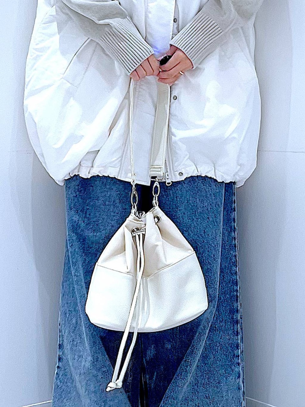 ホワイト系のブルゾン、ブルー系のデニムパンツ、ホワイト系のショルダーバッグを着用したレディースの冬コーディネートの9枚目の写真