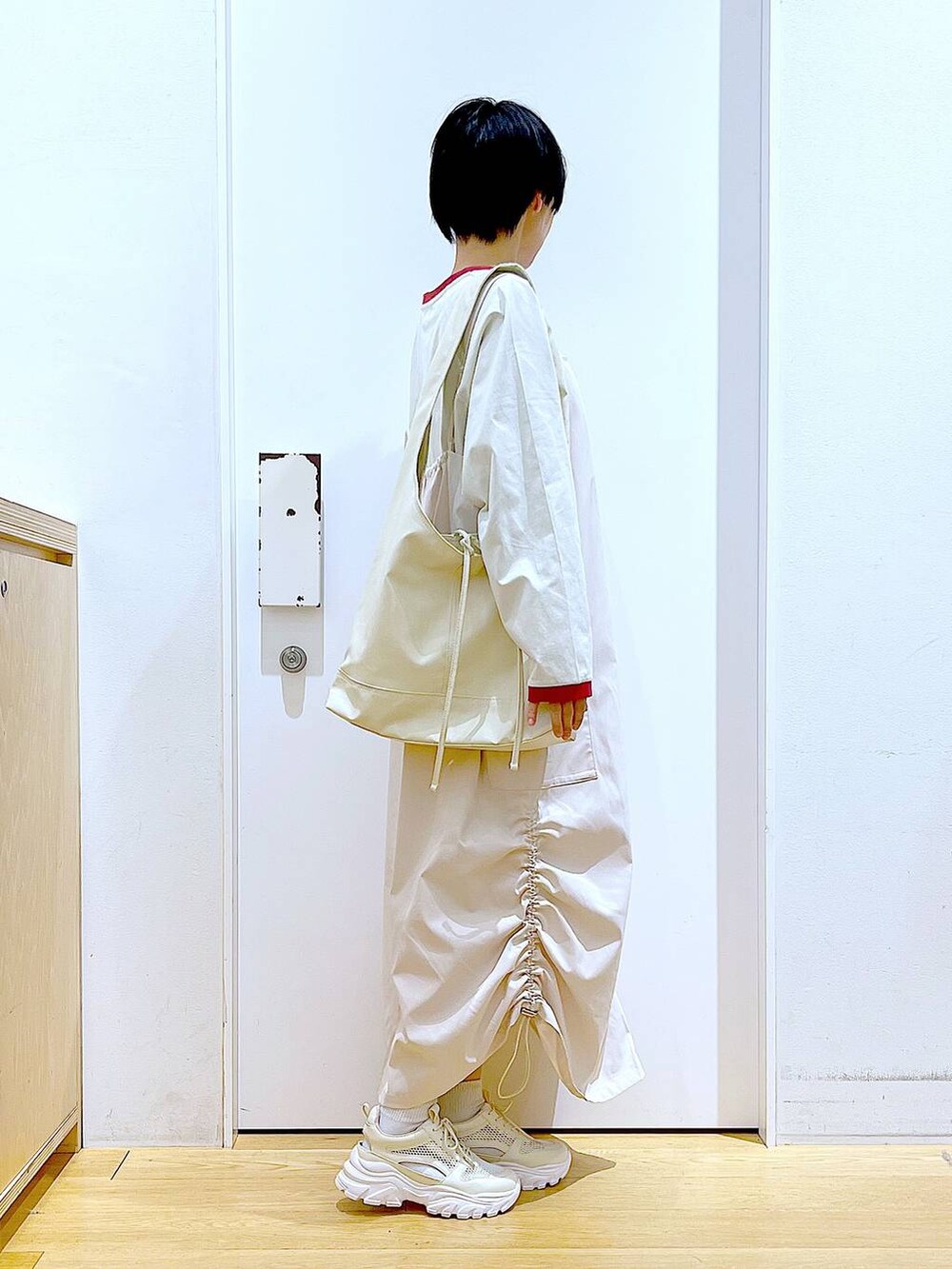 ホワイト系のスニーカー、ベージュ系のジャンパースカート、ベージュ系のTシャツ/カットソーを着用したレディースの春コーディネートの4枚目の写真