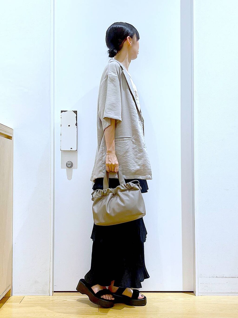 ブラック系のスカート、ブラック系のサンダル、ブラウン系のショルダーバッグを着用したレディースの夏コーディネートの4枚目の写真