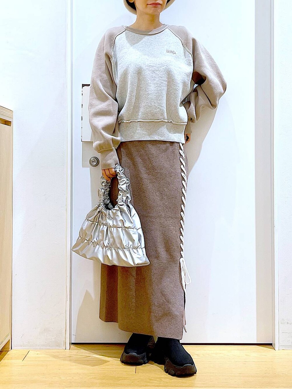 ブラック系のブーツ、ブラウン系のスカート、シルバー系のショルダーバッグを着用したレディースの冬コーディネートの6枚目の写真