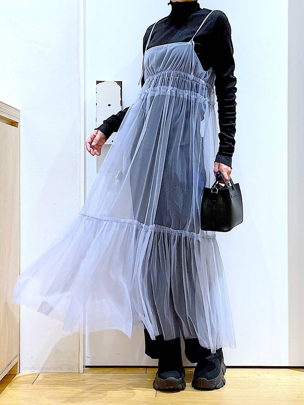 グレー系のデニムパンツ、ブルー系のワンピース、ブラック系のTシャツ/カットソーを着用したレディースの春コーディネートの6枚目の写真