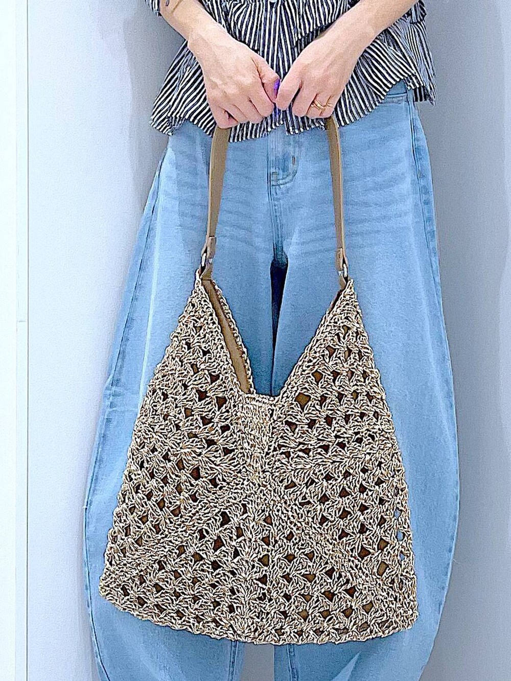 ブルー系のデニムパンツ、ベージュ系のトートバッグ、ホワイト系のスニーカーを着用したレディースの夏コーディネートの9枚目の写真