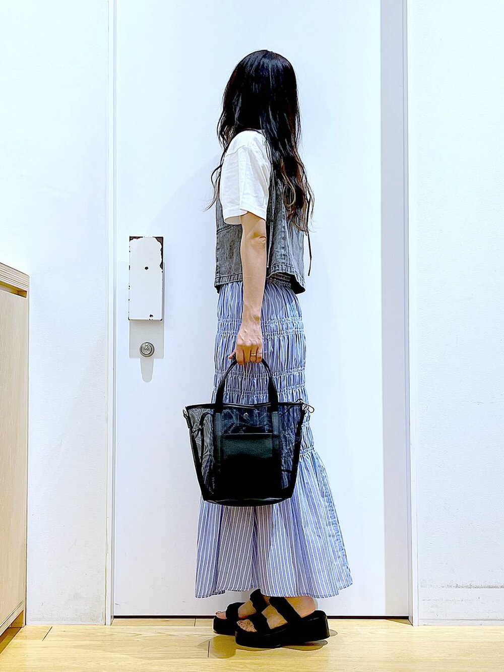 ブラック系のサンダル、ブラック系のトートバッグ、グレー系のベストを着用したレディースの夏コーディネートの3枚目の写真