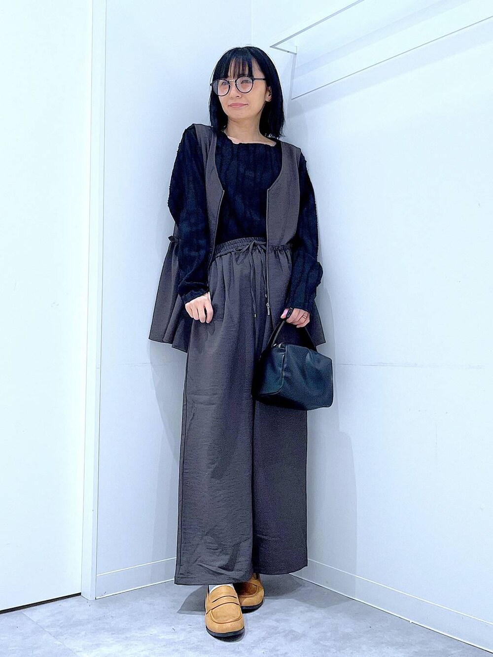 グレー系のその他パンツ、ブラック系のTシャツ/カットソー、ブラック系のショルダーバッグを着用したレディースの春コーディネートの2枚目の写真