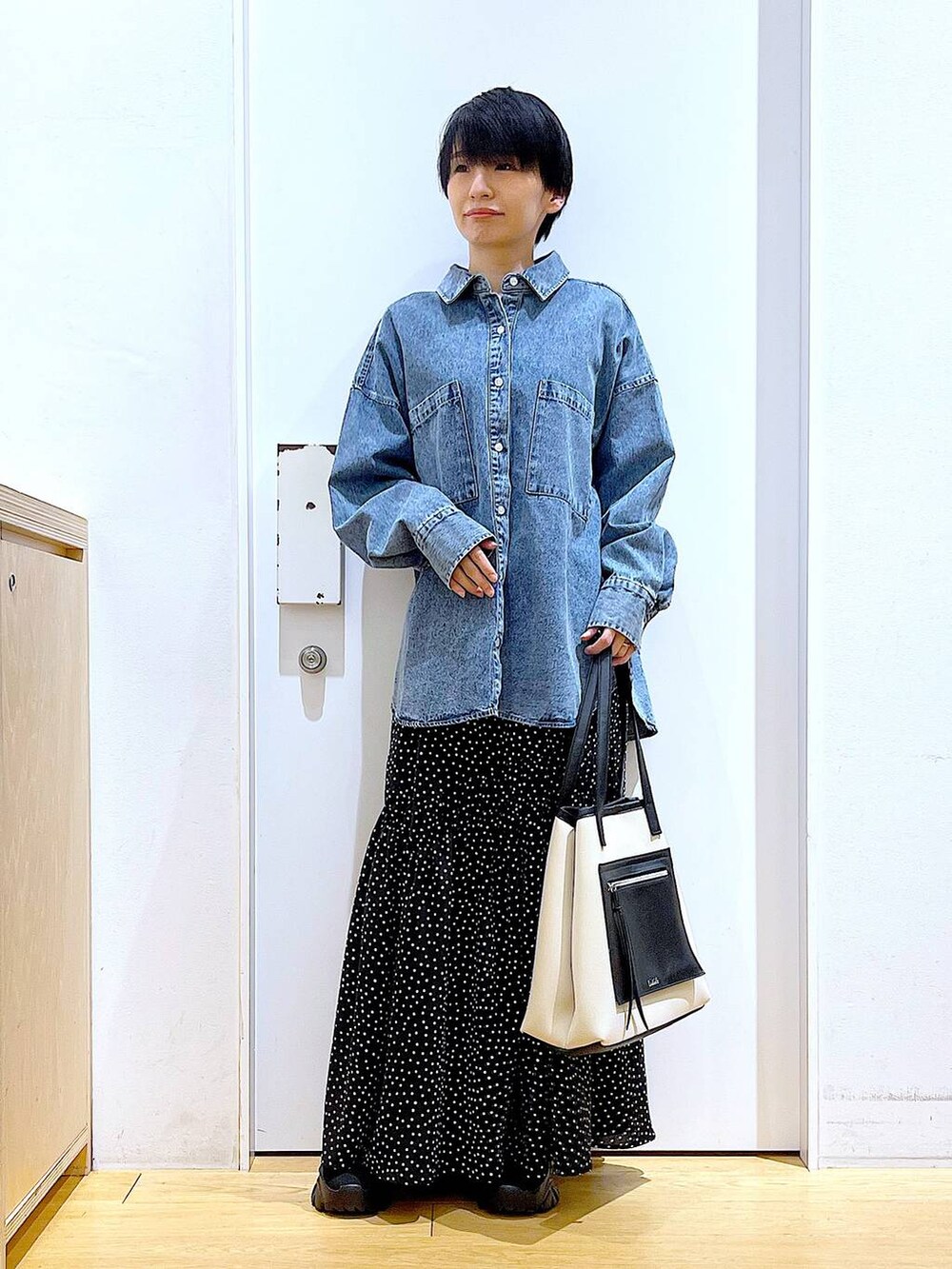 ブラック系のブーツ、ブルー系のシャツ/ブラウス、ホワイト系のトートバッグを着用したレディースの春コーディネートの2枚目の写真