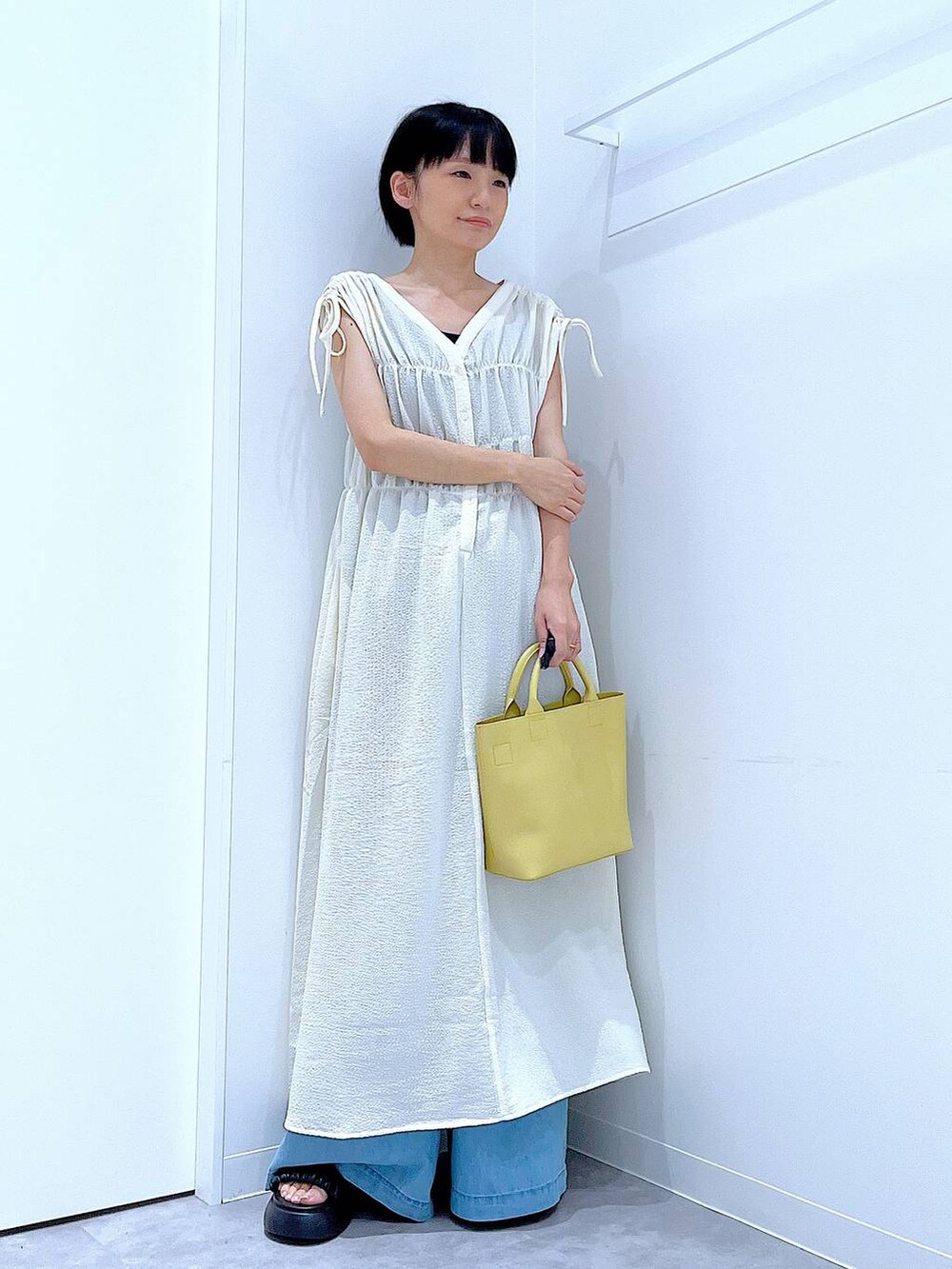 ブラック系のサンダル、ブルー系のデニムパンツ、ベージュ系のワンピースを着用したレディースの夏コーディネートの2枚目の写真