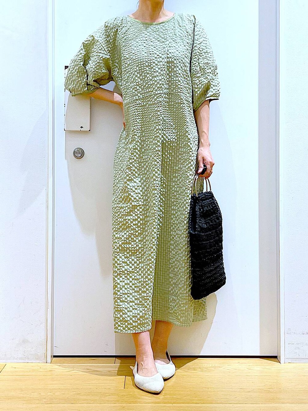 グリーン系のワンピース、ホワイト系のパンプス、ブラック系のハンドバッグを着用したレディースの春コーディネートの6枚目の写真