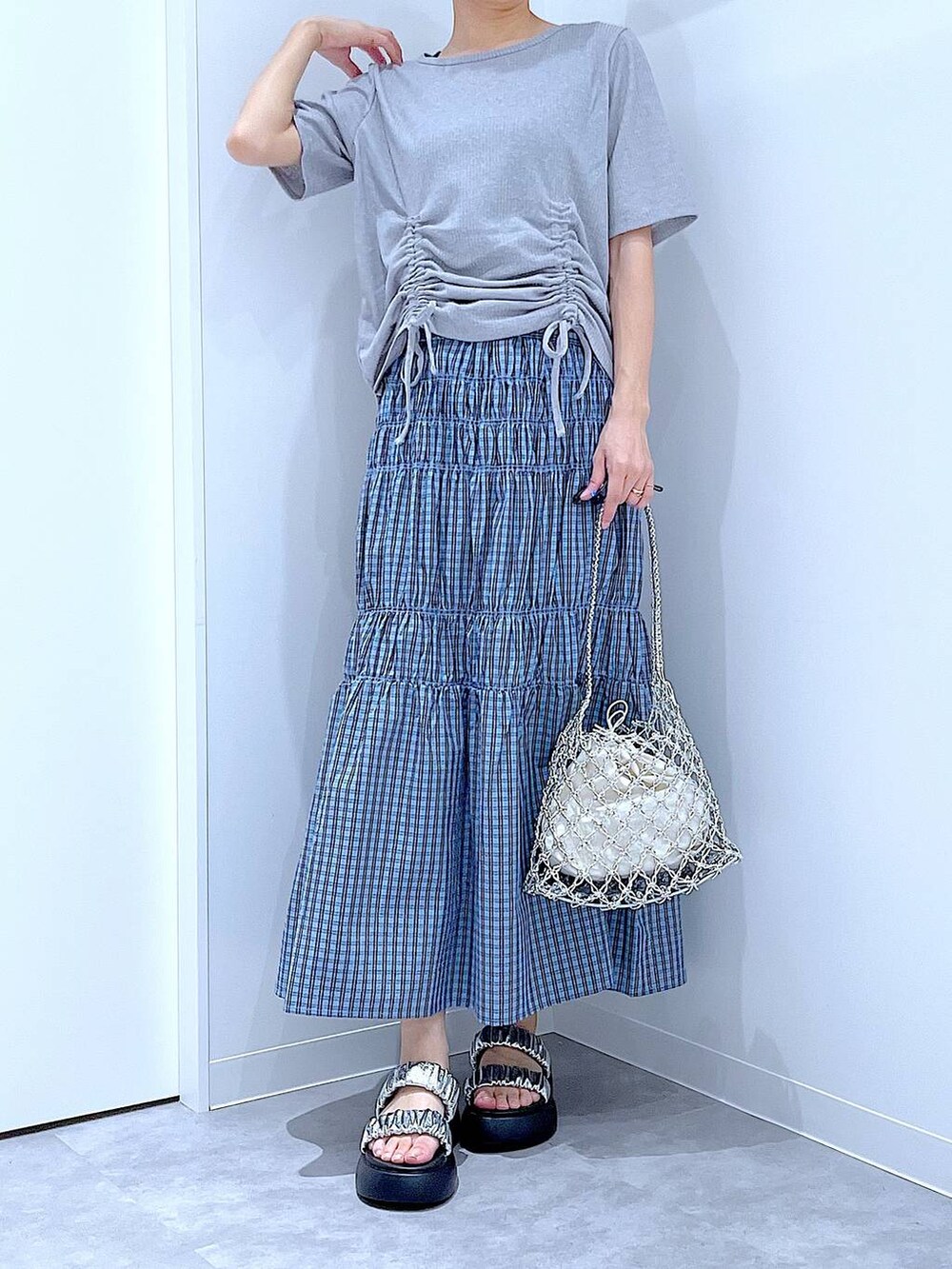 シルバー系のかごバッグ、シルバー系のサンダル、ブルー系のスカートを着用したレディースの夏コーディネートの6枚目の写真