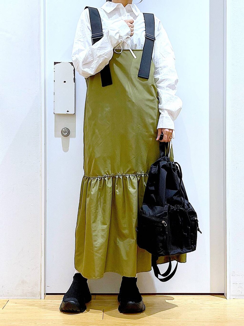 ブラック系のショルダーバッグ、グリーン系のワンピース、ホワイト系のシャツ/ブラウスを着用したレディースの春コーディネートの6枚目の写真