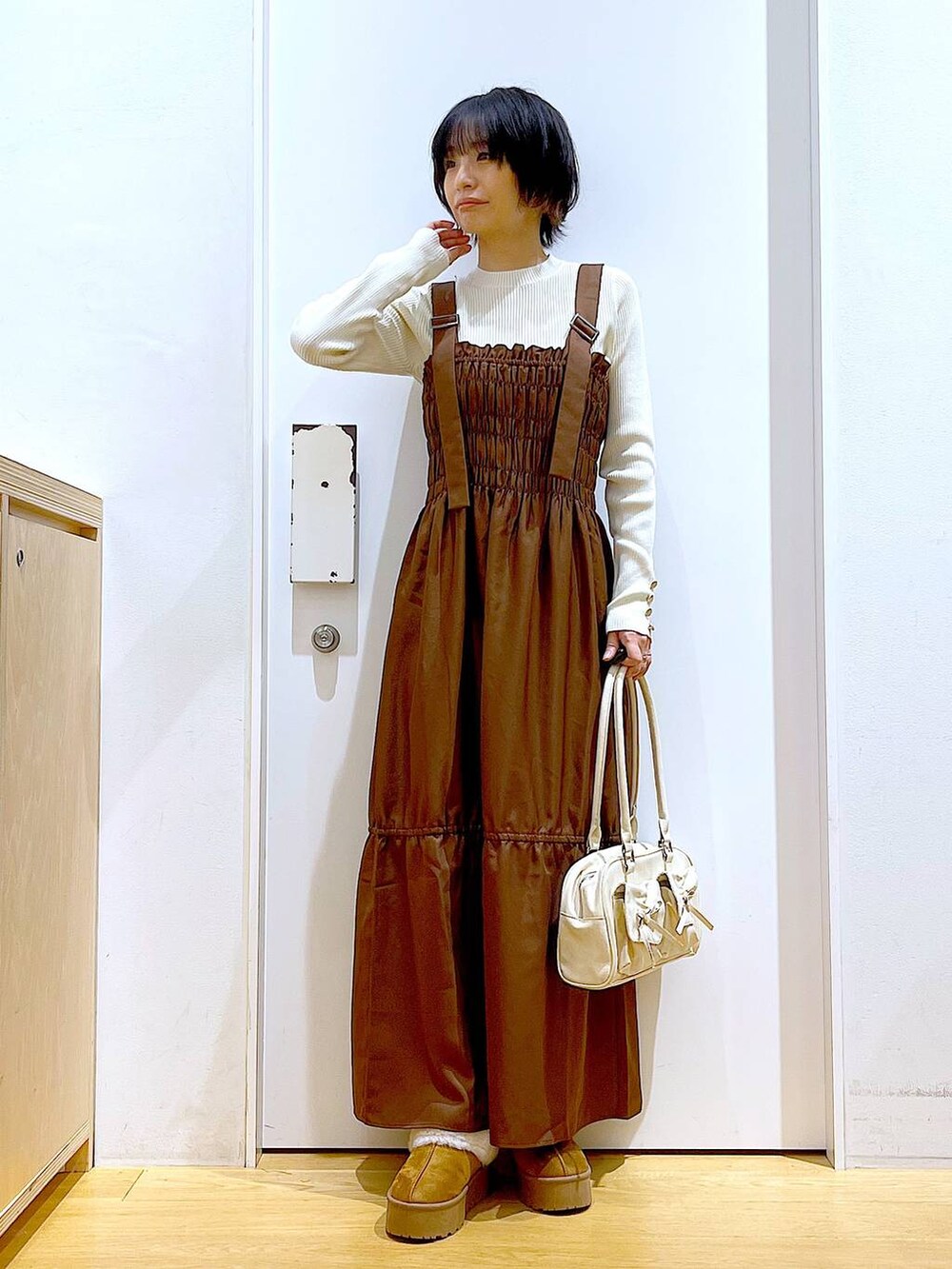 ホワイト系のニット/セーター、ホワイト系のハンドバッグ、ベージュ系のスリッポンを着用したレディースの冬コーディネートの2枚目の写真