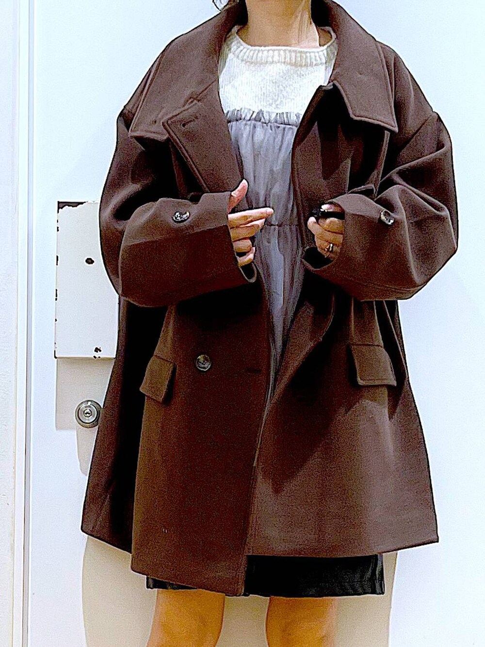 ブラウン系のステンカラーコート、ブラック系のハンドバッグ、ブラック系のブーツを着用したレディースの冬コーディネートの7枚目の写真