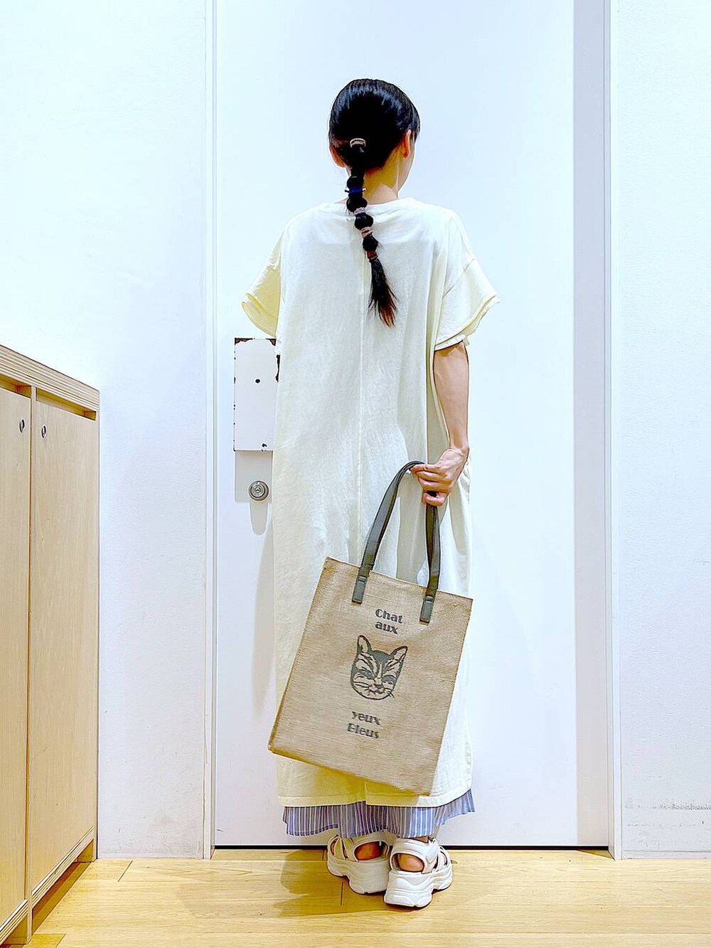 ホワイト系のサンダル、ベージュ系のワンピース、グレー系のトートバッグを着用したレディースの夏コーディネートの5枚目の写真