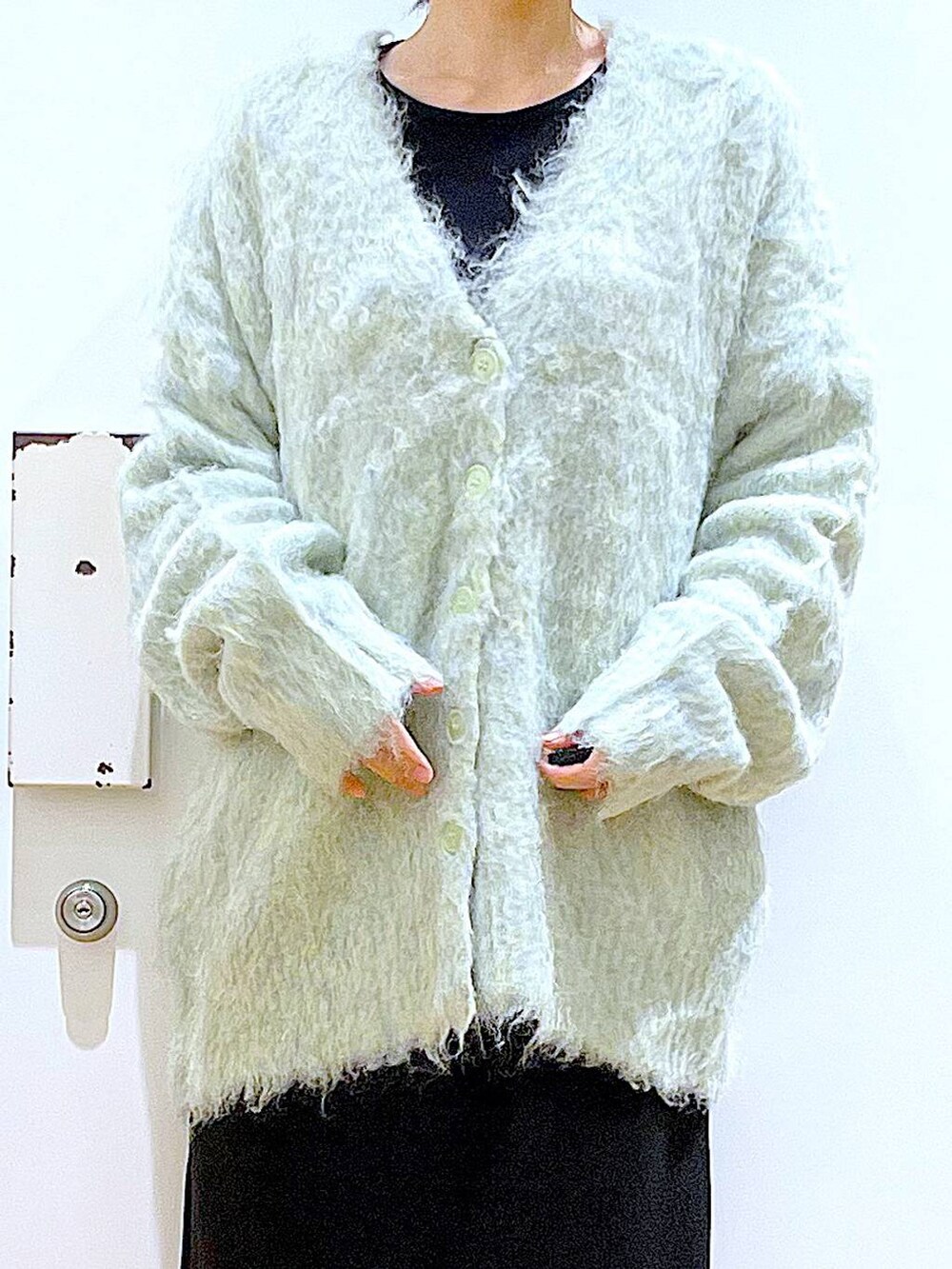 グリーン系のカーディガン/ボレロ、ブラック系のブーツ、ブラック系のスカートを着用したレディースの冬コーディネートの7枚目の写真