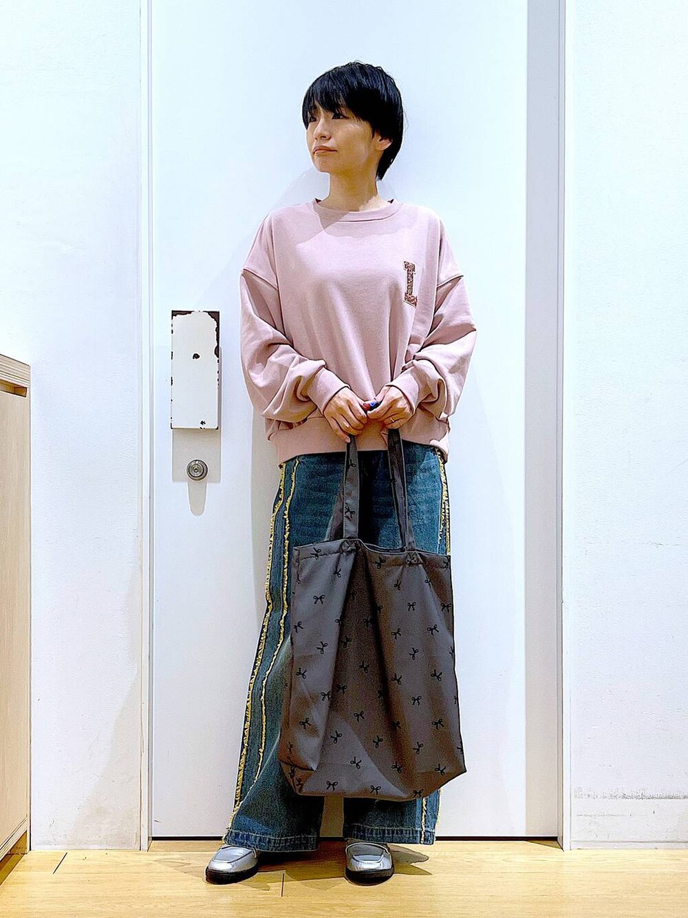 シルバー系のローファー、ブルー系のデニムパンツ、その他のトートバッグを着用したレディースの春コーディネートの2枚目の写真