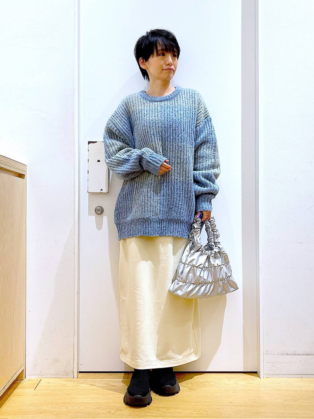 ブルー系のニット/セーター、ブラック系のブーツ、シルバー系のショルダーバッグを着用したレディースの冬コーディネートの2枚目の写真