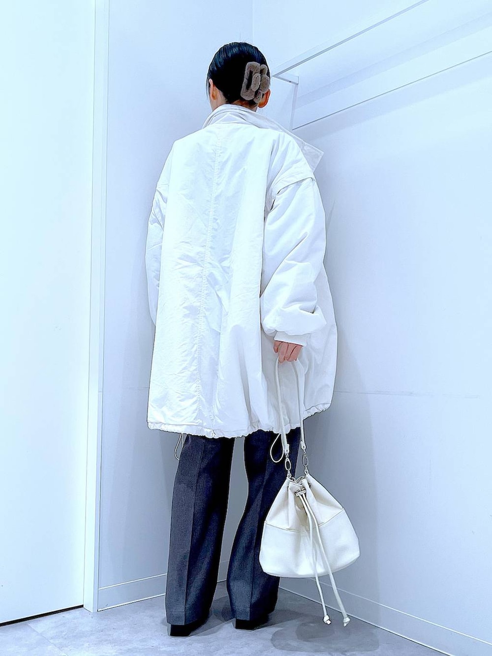 ホワイト系のブルゾン、ホワイト系のショルダーバッグ、ブラック系のブーツを着用したレディースの冬コーディネートの5枚目の写真