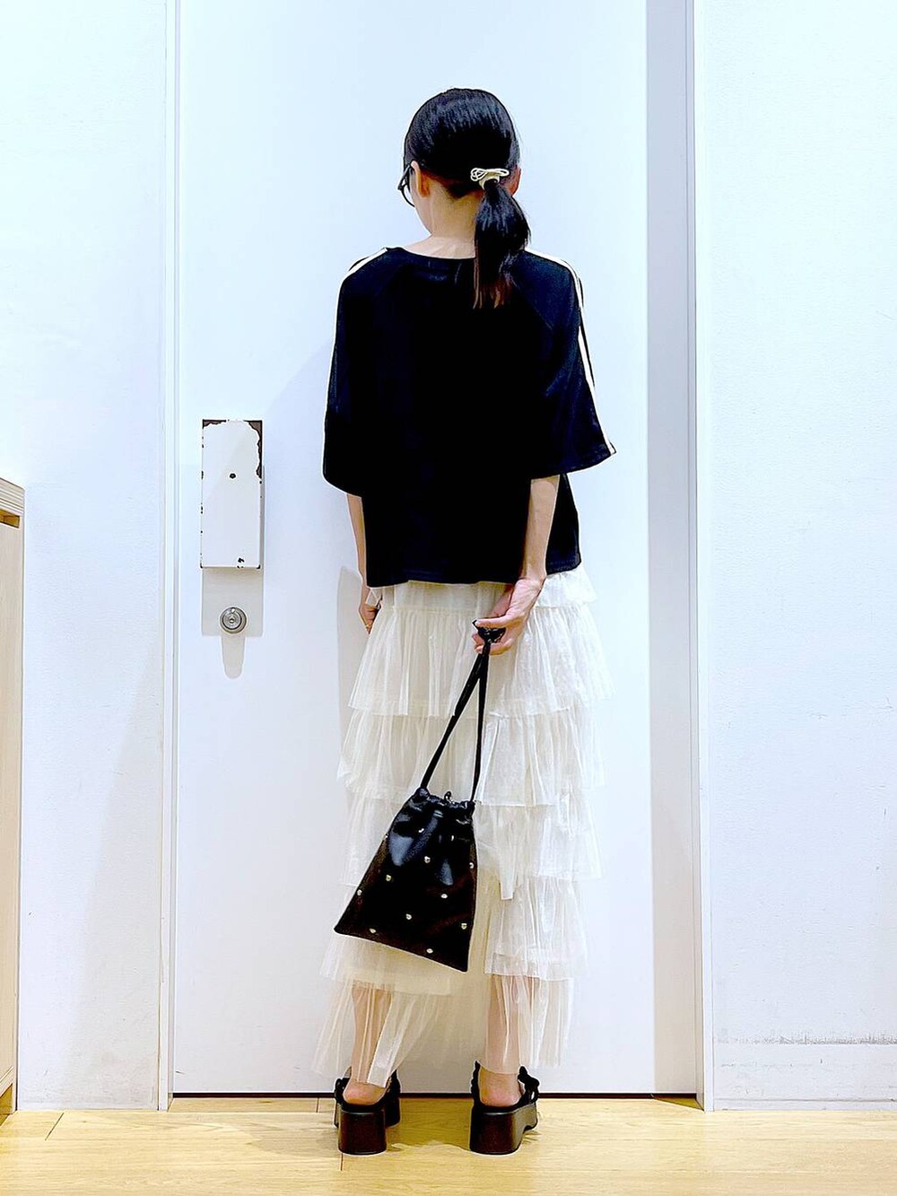 ブラック系のサンダル、ブラック系のショルダーバッグ、ベージュ系のスカートを着用したレディースの夏コーディネートの5枚目の写真