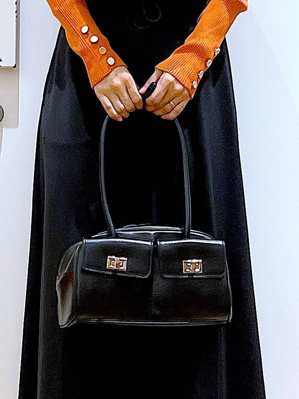 オレンジ系のニット/セーター、ブラウン系のベスト、ブラック系のハンドバッグを着用したレディースの秋コーディネートの9枚目の写真