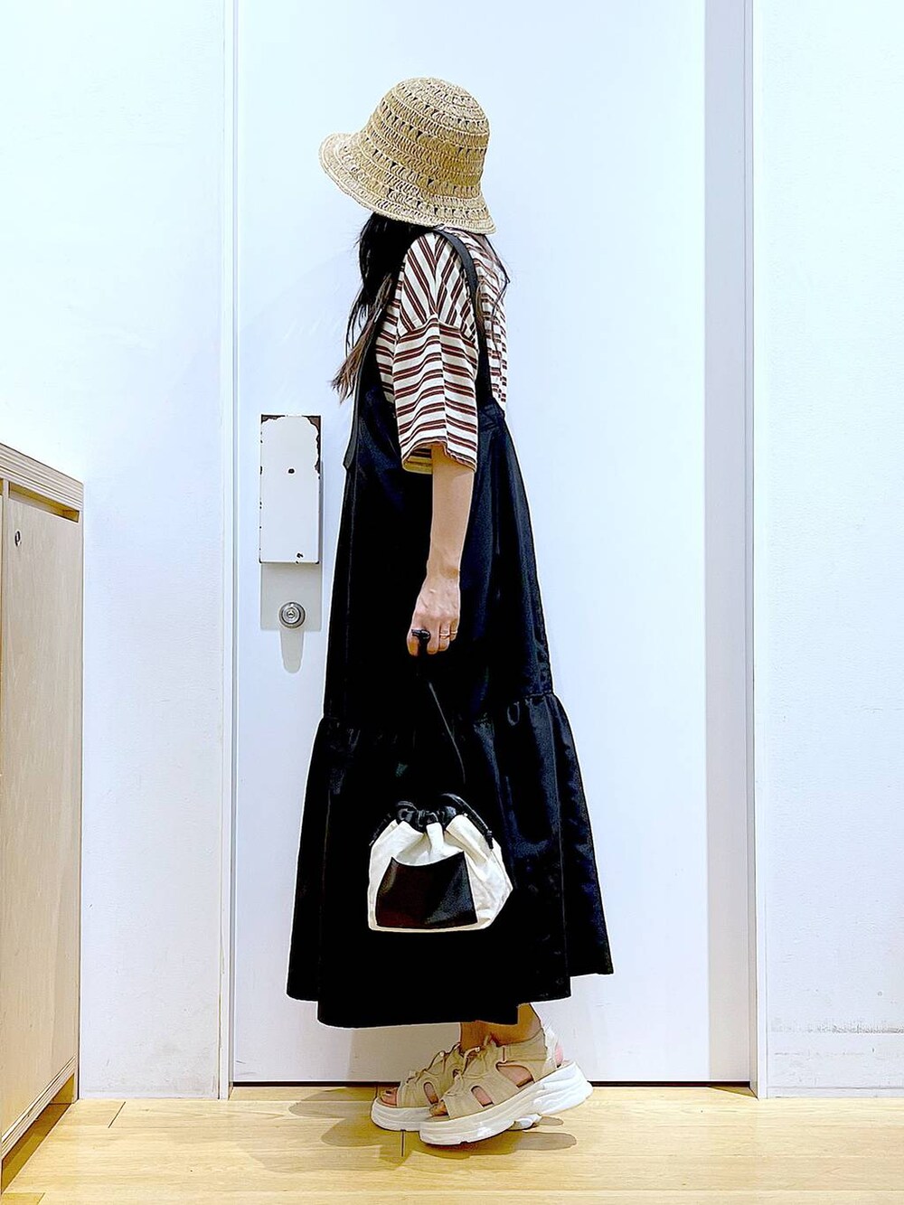 ホワイト系のショルダーバッグ、ブラック系のワンピース、ベージュ系のサンダルを着用したレディースの春コーディネートの3枚目の写真