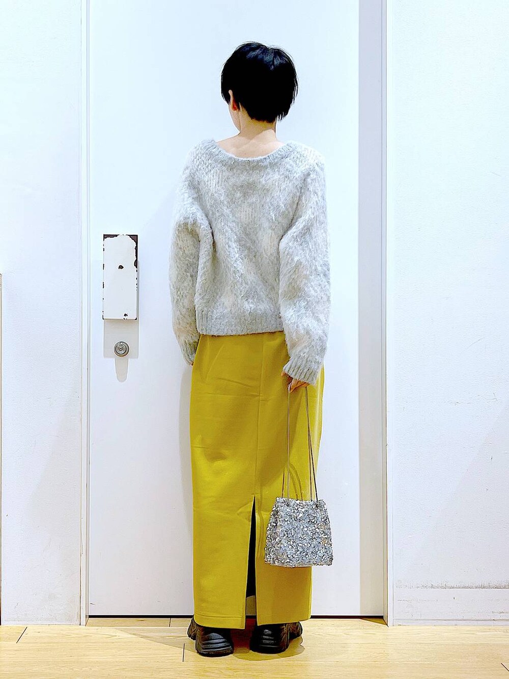 ブラック系のブーツ、イエロー系のスカート、その他のショルダーバッグを着用したレディースの冬コーディネートの5枚目の写真