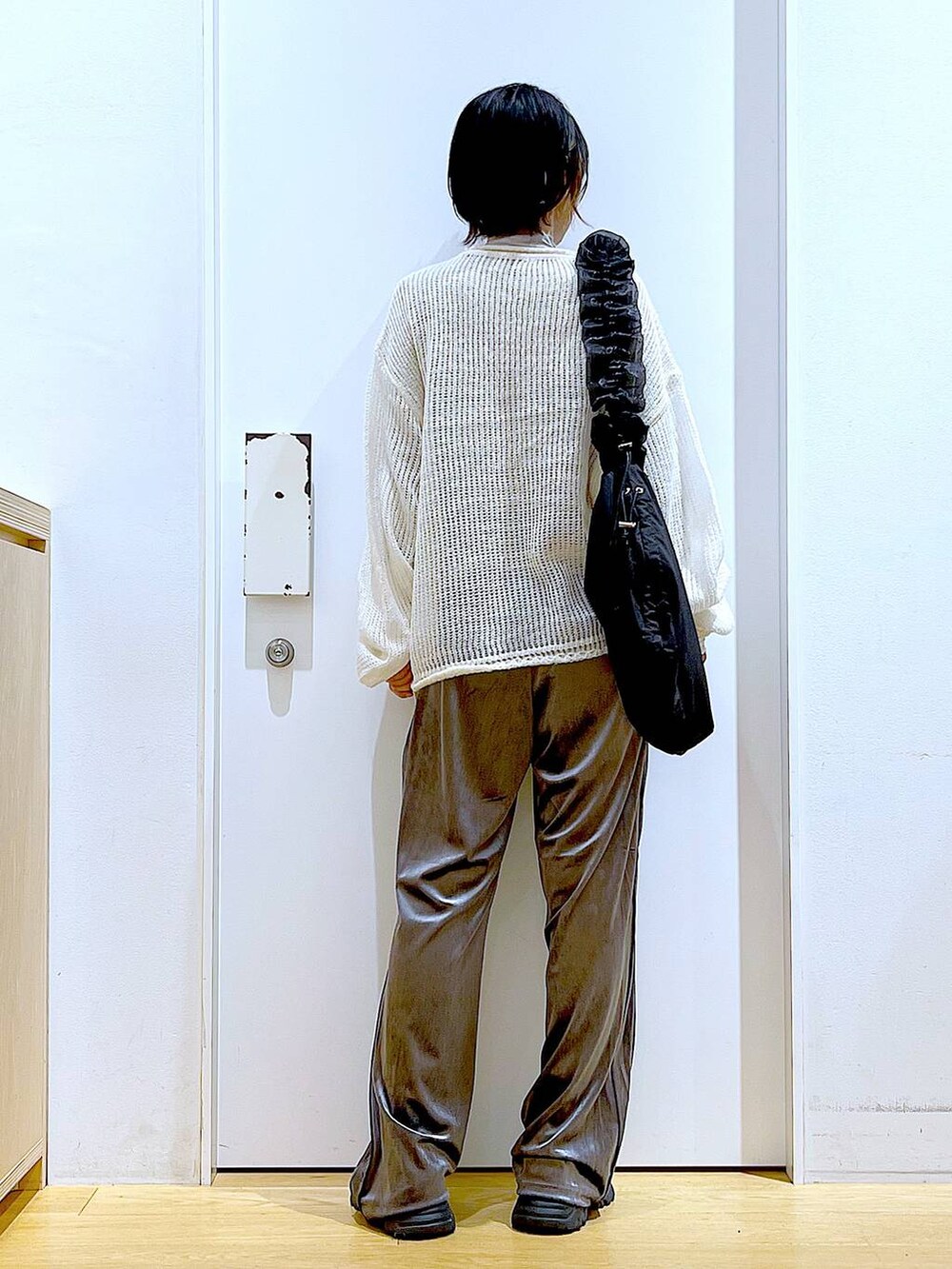 ブラック系のショルダーバッグ、ブラック系のブーツ、ホワイト系のニット/セーターを着用したレディースの冬コーディネートの5枚目の写真