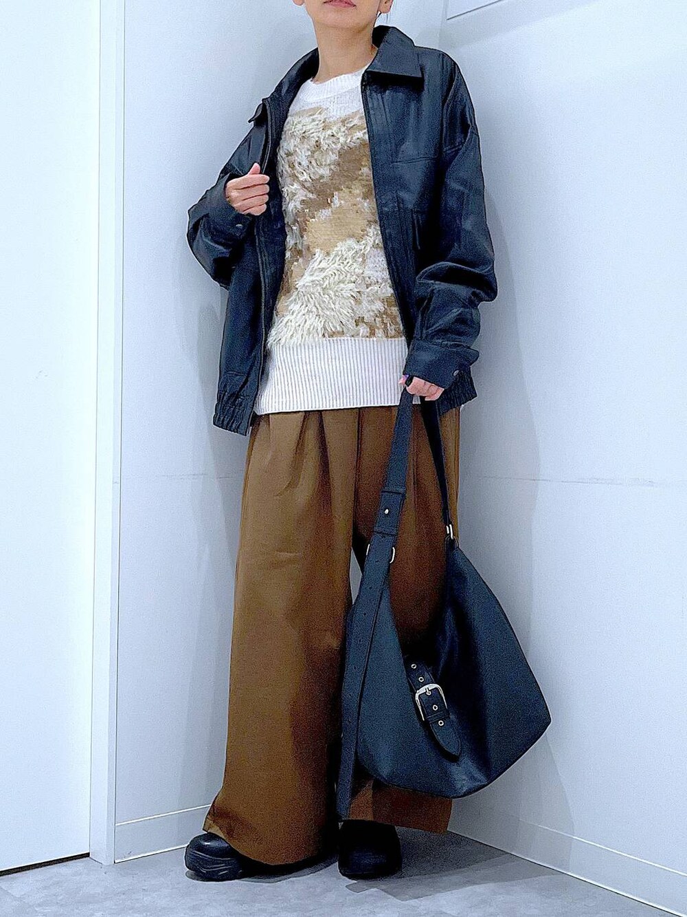 ブラック系のブルゾン、ブラック系のブーツ、ベージュ系のニット/セーターを着用したレディースの秋コーディネートの6枚目の写真