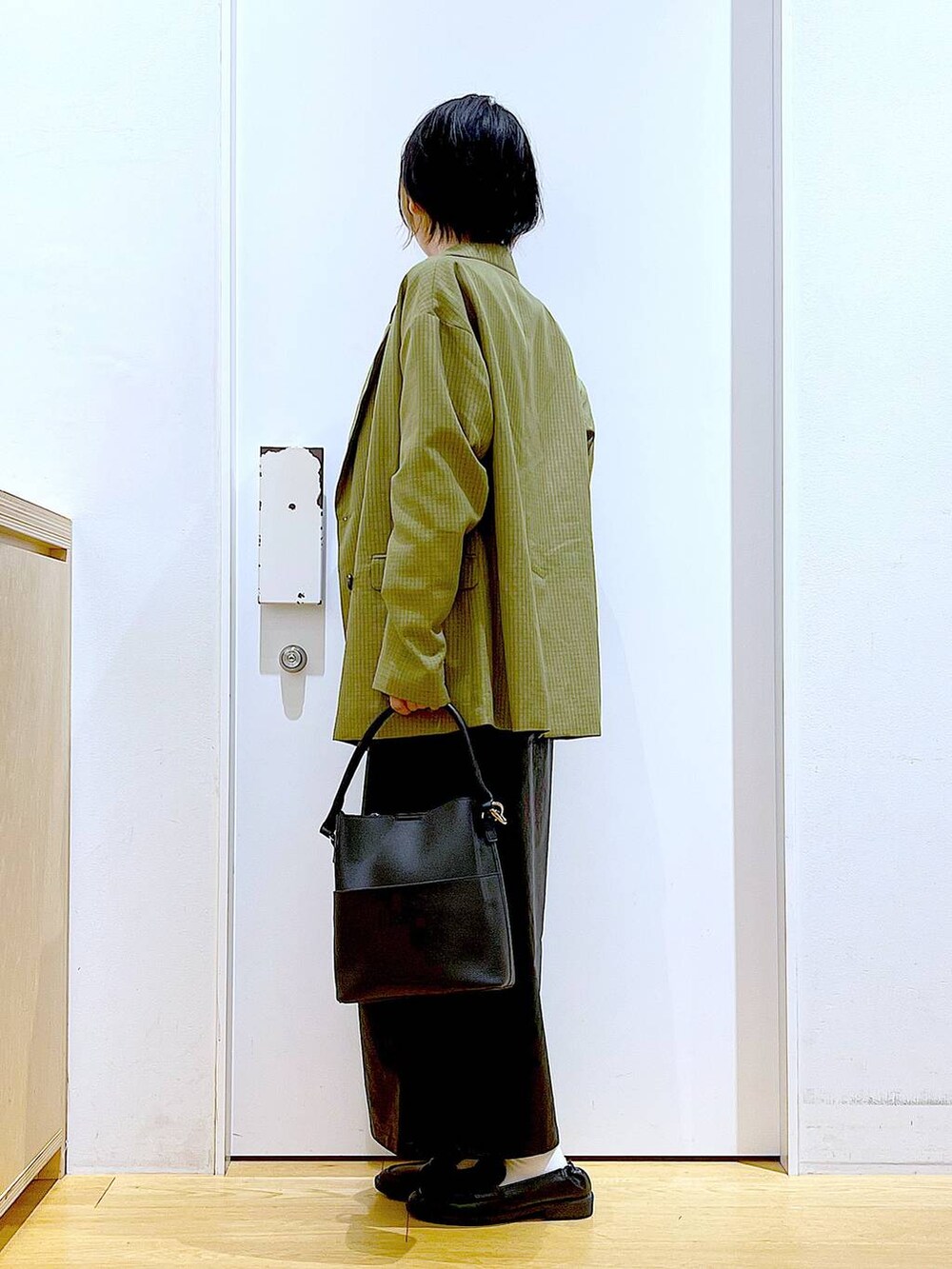 ホワイト系のベスト、ブラック系のスカート、ブラック系のショルダーバッグを着用したレディースの秋コーディネートの3枚目の写真