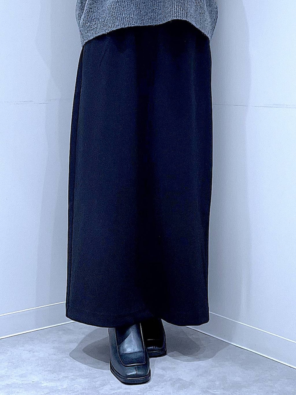 ブラック系のスカート、ブラック系のブーツ、ホワイト系のショルダーバッグを着用したレディースの冬コーディネートの8枚目の写真