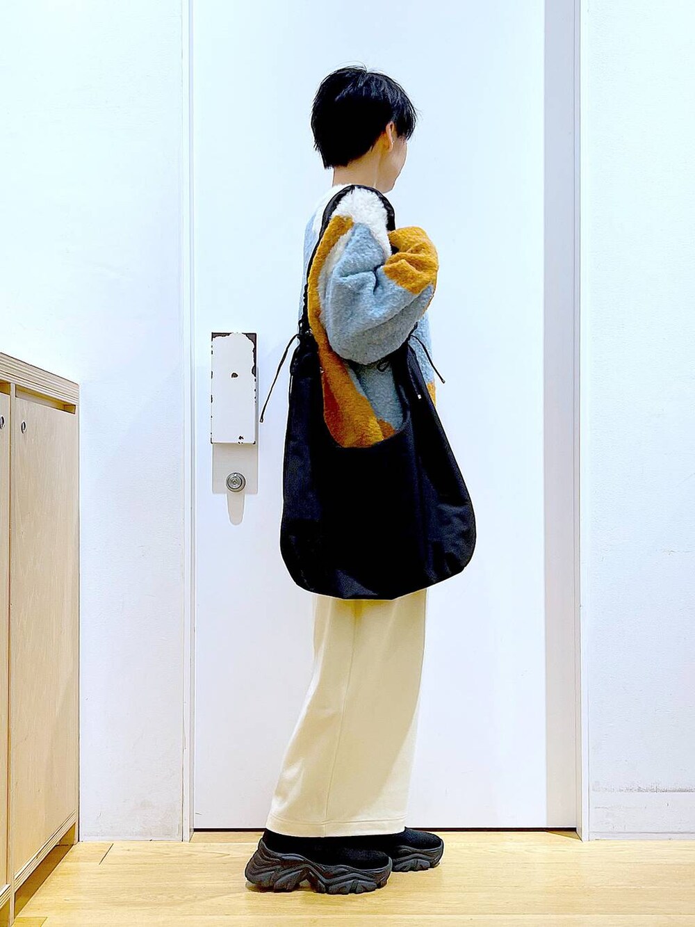 ブラック系のショルダーバッグ、ブラック系のブーツ、オレンジ系のニット/セーターを着用したレディースの冬コーディネートの4枚目の写真