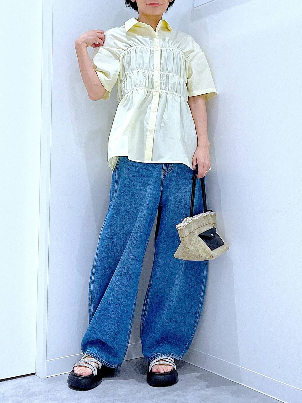 ブルー系のデニムパンツ、ベージュ系のショルダーバッグ、シルバー系のサンダルを着用したレディースの夏コーディネートの6枚目の写真