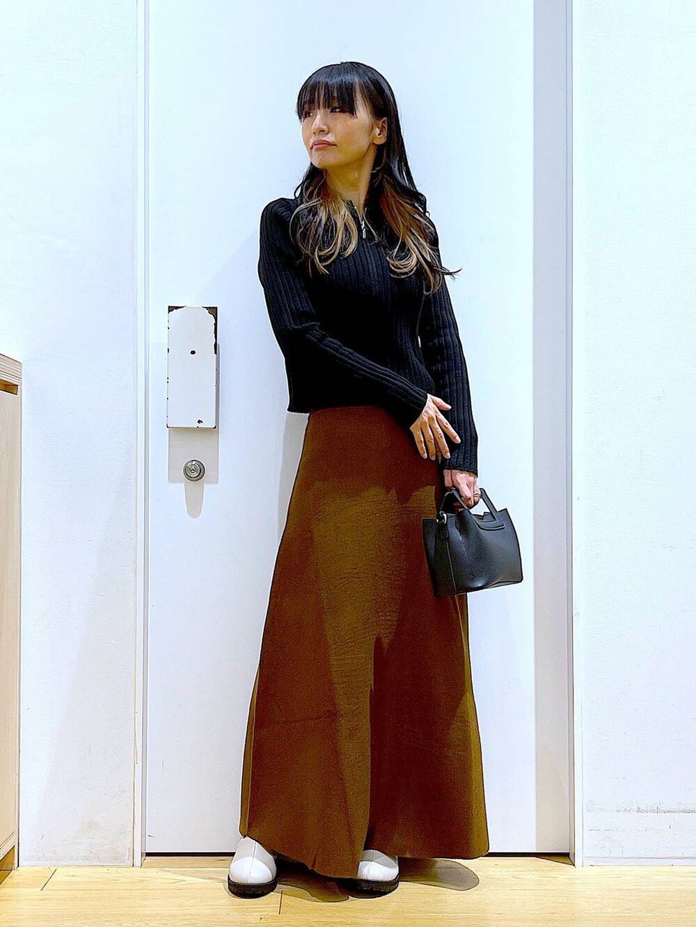 ブラック系のカーディガン/ボレロ、ブラウン系のスカート、ベージュ系のブーツを着用したレディースの冬コーディネートの2枚目の写真