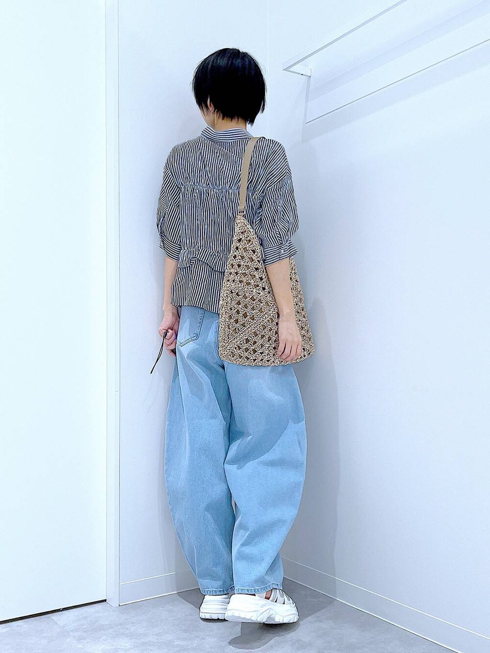 ブルー系のデニムパンツ、ベージュ系のトートバッグ、ホワイト系のスニーカーを着用したレディースの夏コーディネートの6枚目の写真