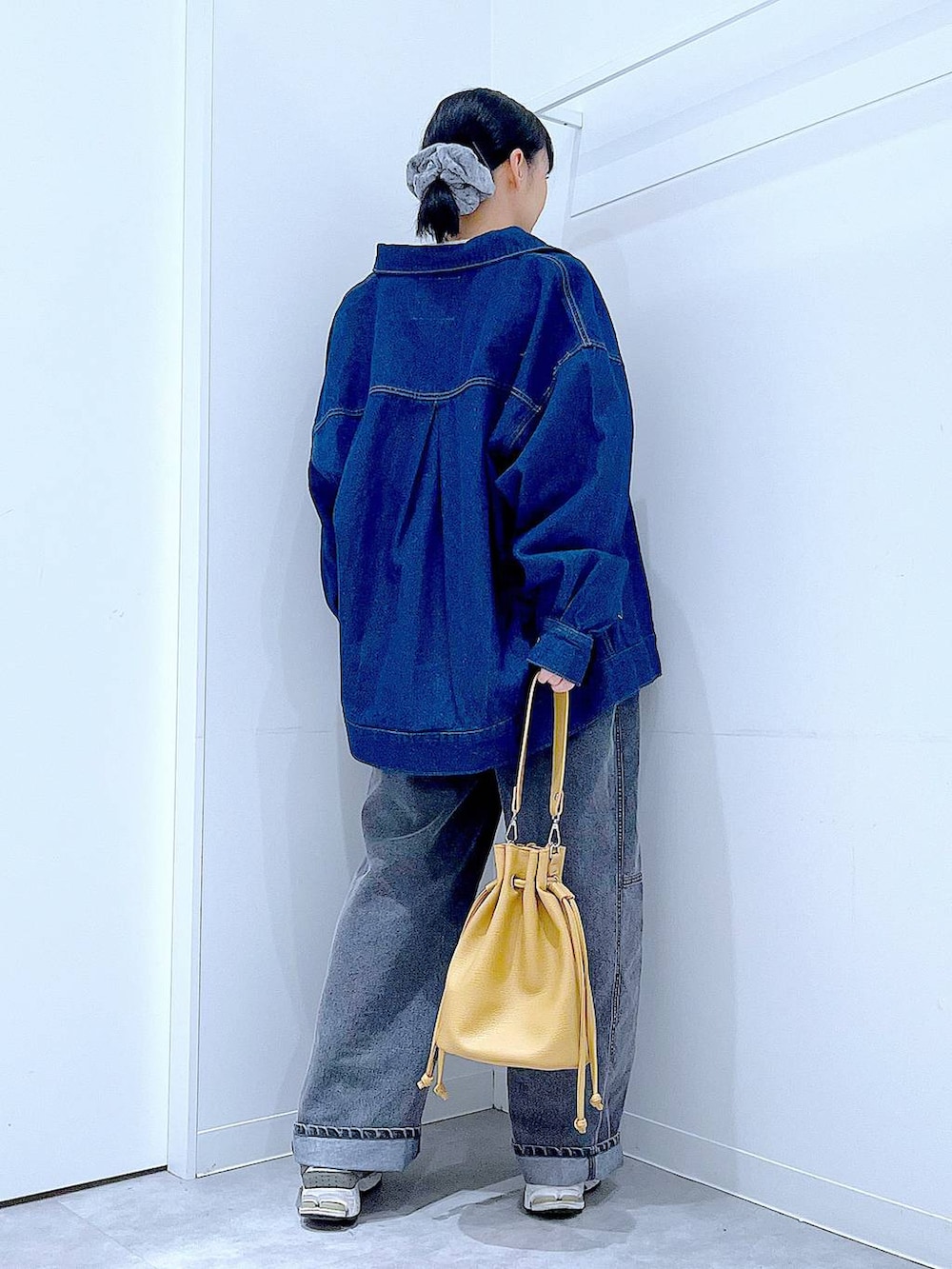 ブルー系のデニムジャケット、ブラック系のデニムパンツ、ブラウン系のショルダーバッグを着用したレディースの春コーディネートの5枚目の写真