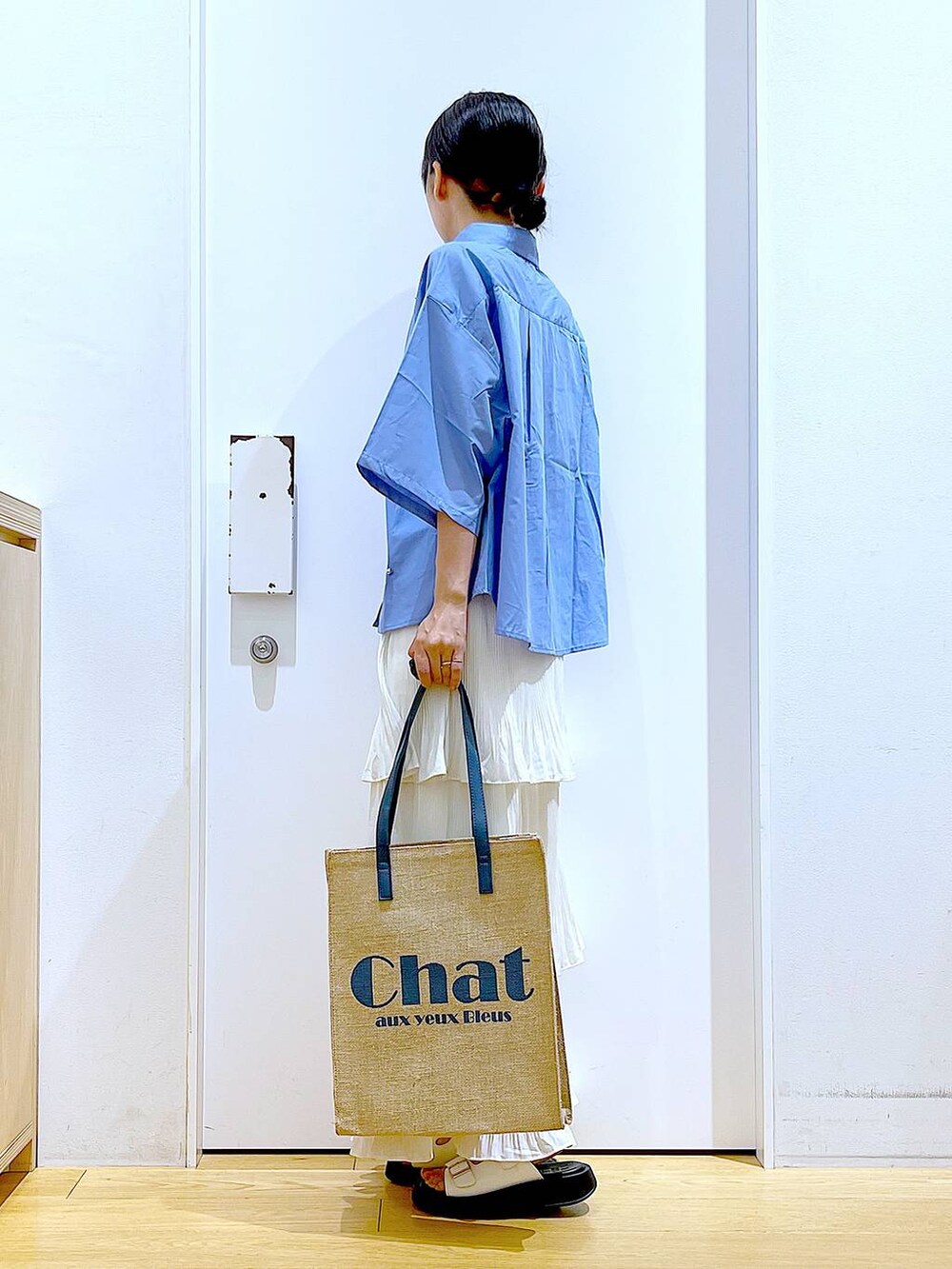 ベージュ系のスカート、ブルー系のトートバッグ、ホワイト系のサンダルを着用したレディースの夏コーディネートの3枚目の写真