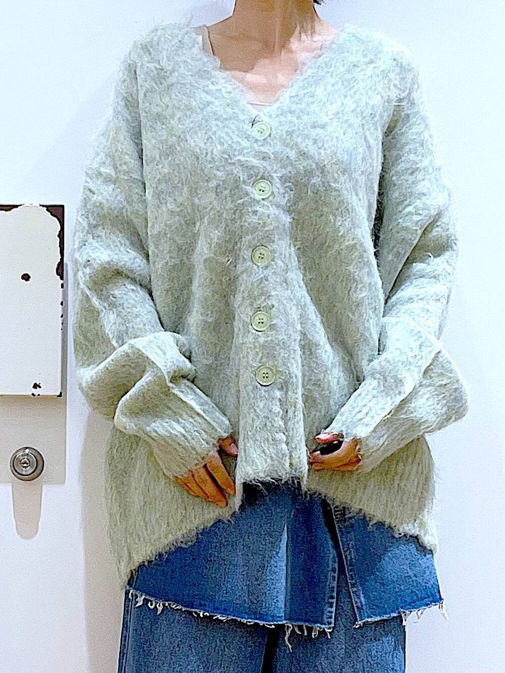 グリーン系のカーディガン/ボレロ、ブラック系のローファー、ブルー系のデニムパンツを着用したレディースの秋コーディネートの7枚目の写真